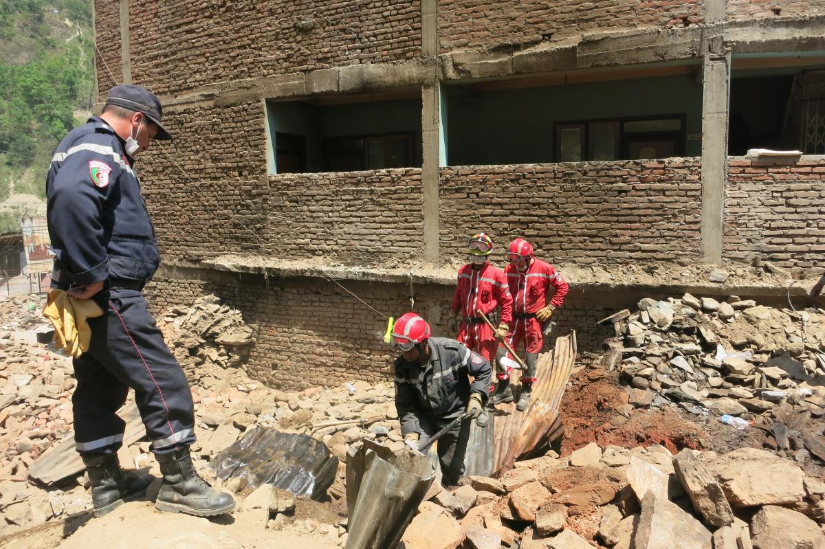 Grupa mężczyzn i ratownicy przeszukują gruzy, Nepal, 2015 rok. Fot. PAH